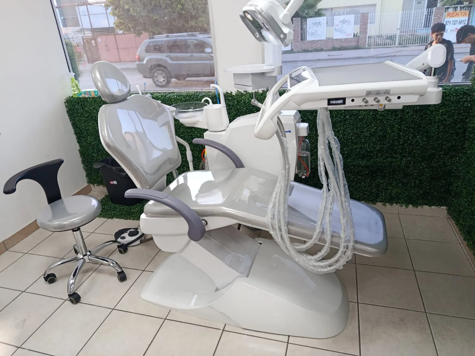 Unidad dental gris instalada frente a un muro verde y ventanales
